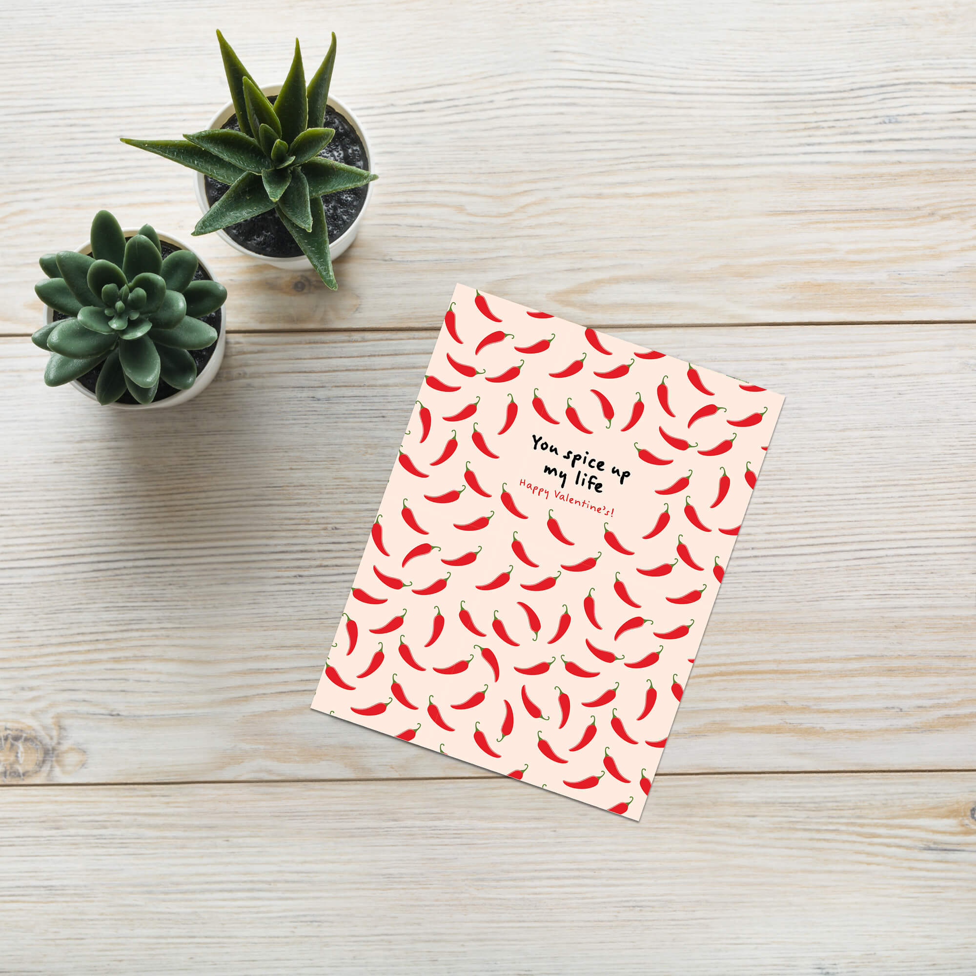 light pink valentines day card with repeating red chilies and center text “You spice up my life — Happy Valentine’s.”