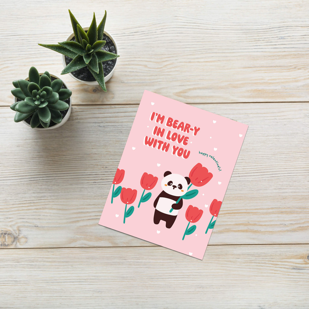 Pink card with panda and flowers on a wooden surface with succulents