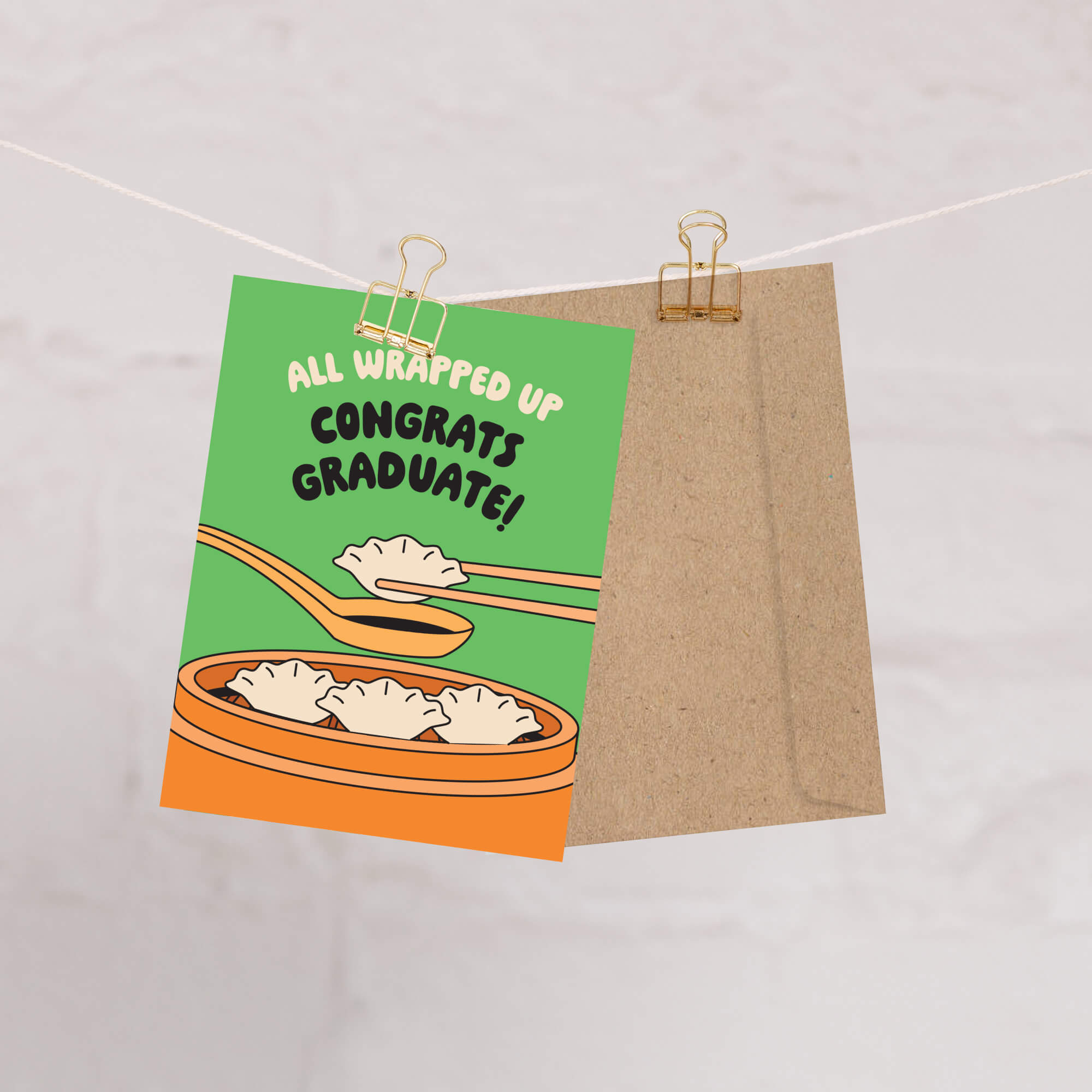 Graduation card with dumplings and text 'All Wrapped Up Congrats Graduate!' on a green background.