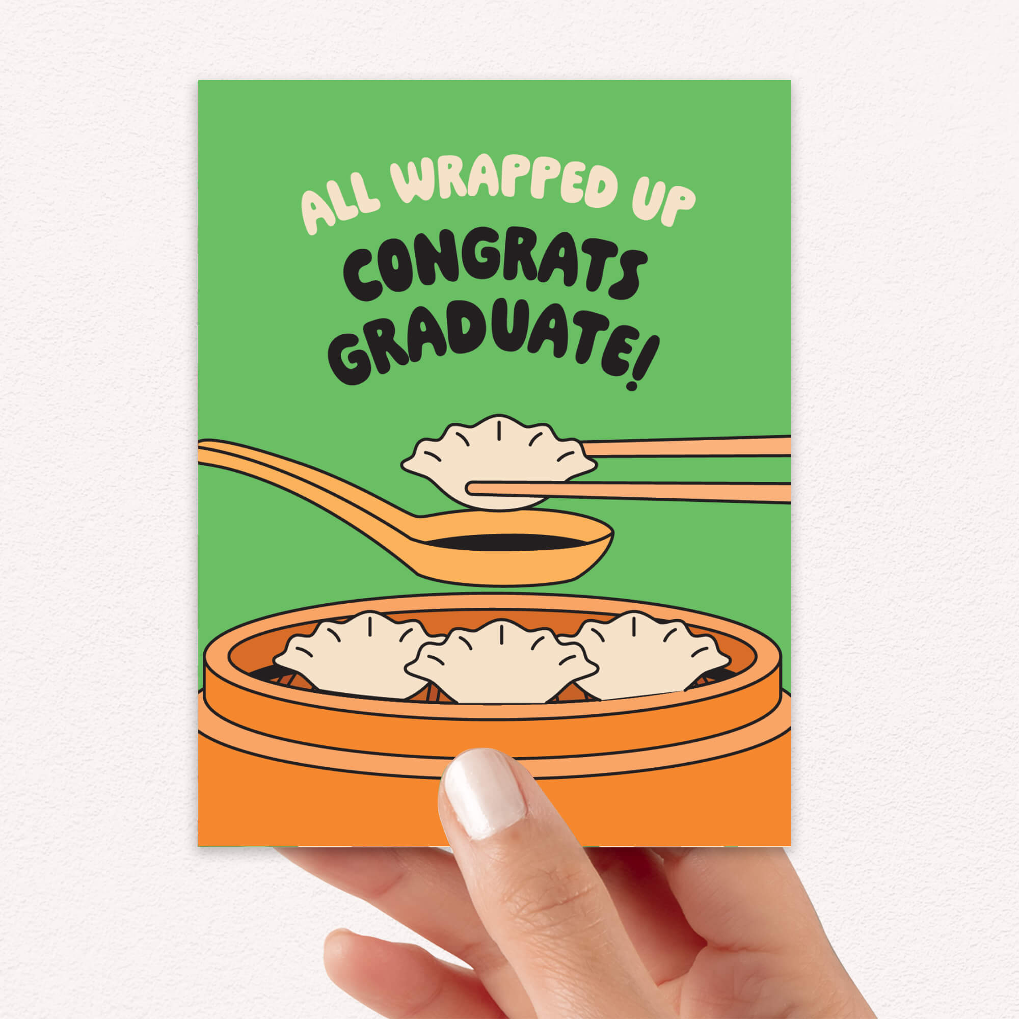 Graduation card with dumplings and text 'All Wrapped Up Congrats Graduate!' on a green background.