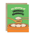 Graduation card with dumplings and text 'All Wrapped Up Congrats Graduate!' on a green background.