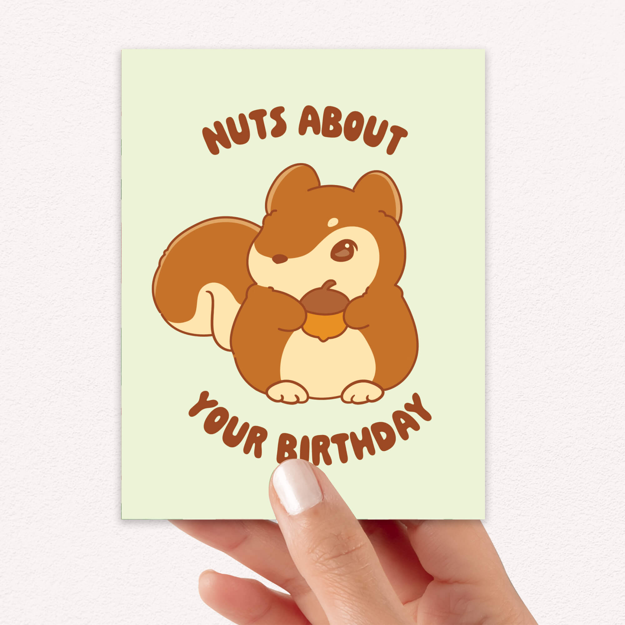 Greeting card with a cartoon squirrel holding a nut and text 'Nuts About Your Birthday' held by a hand.