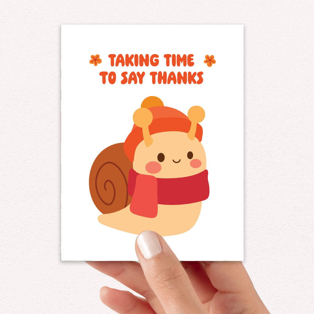 fall Card with a cartoon snail wearing a hat and scarf, text 'Taking Time to Say Thanks', held by a hand.