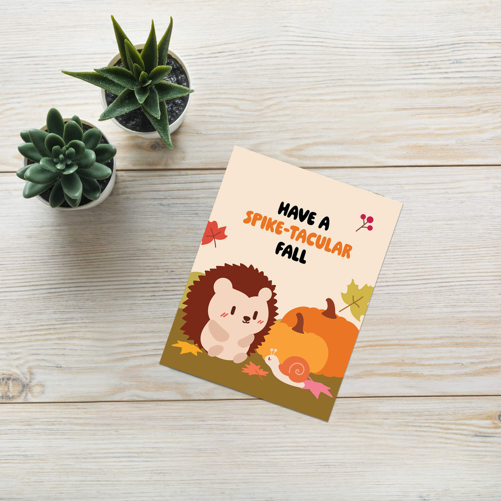 fall Greeting card with hedgehog and pumpkin illustration on a wooden surface with plants.