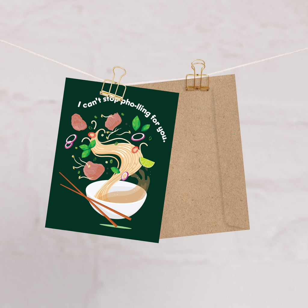 greting Card with pho illustration and text on a green background, clipped to a brown paper bag against a light background.