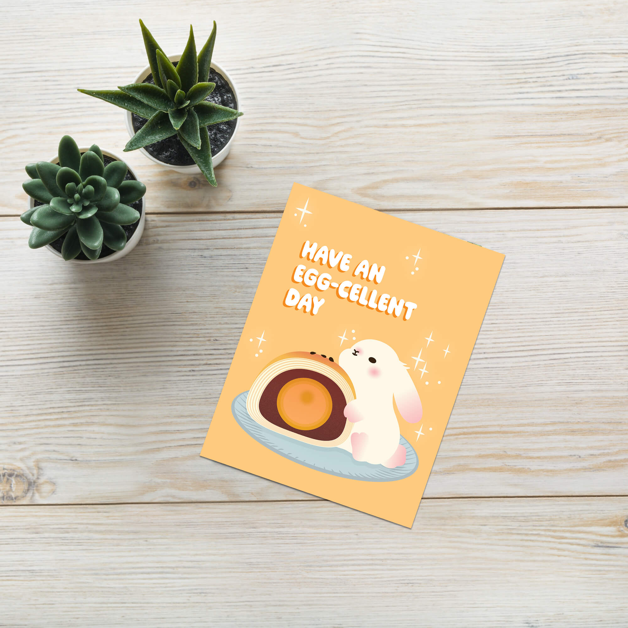 mid autumn festival Greeting card with a cute white bunny and egg yolk pastry, and text 'Have an EGG-cellent day' on a yellow background.