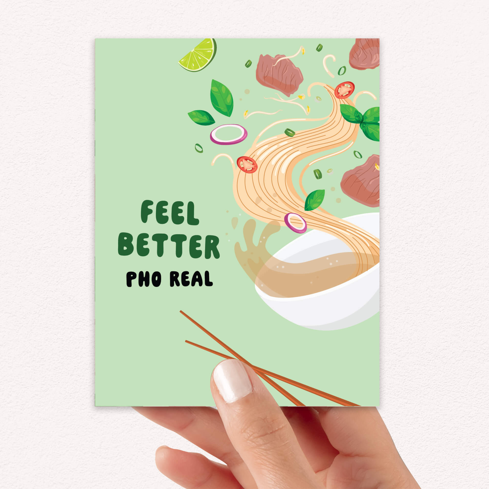 Card with pho illustration and 'Feel Better Pho Real' text held by a hand.