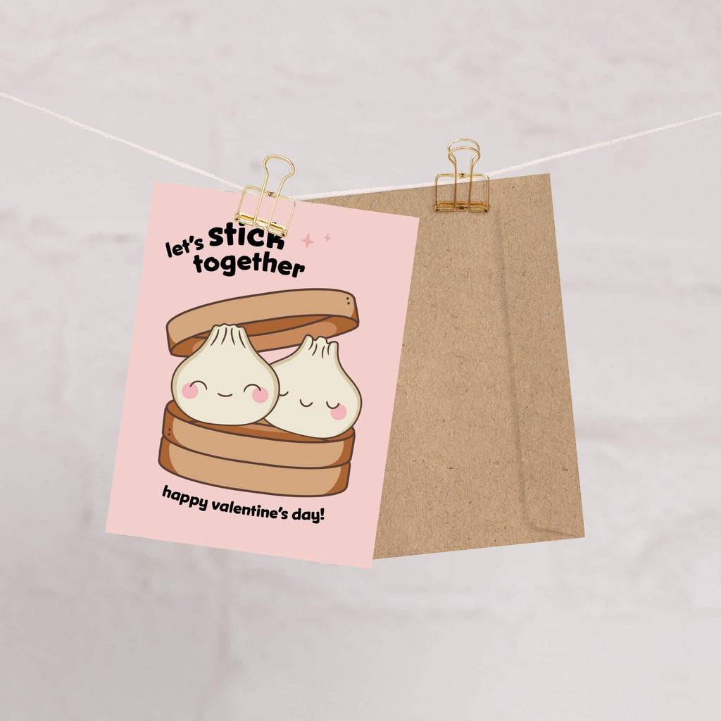Valentine's Day card with cartoon dumplings and text on a pink background, hanging on a string.