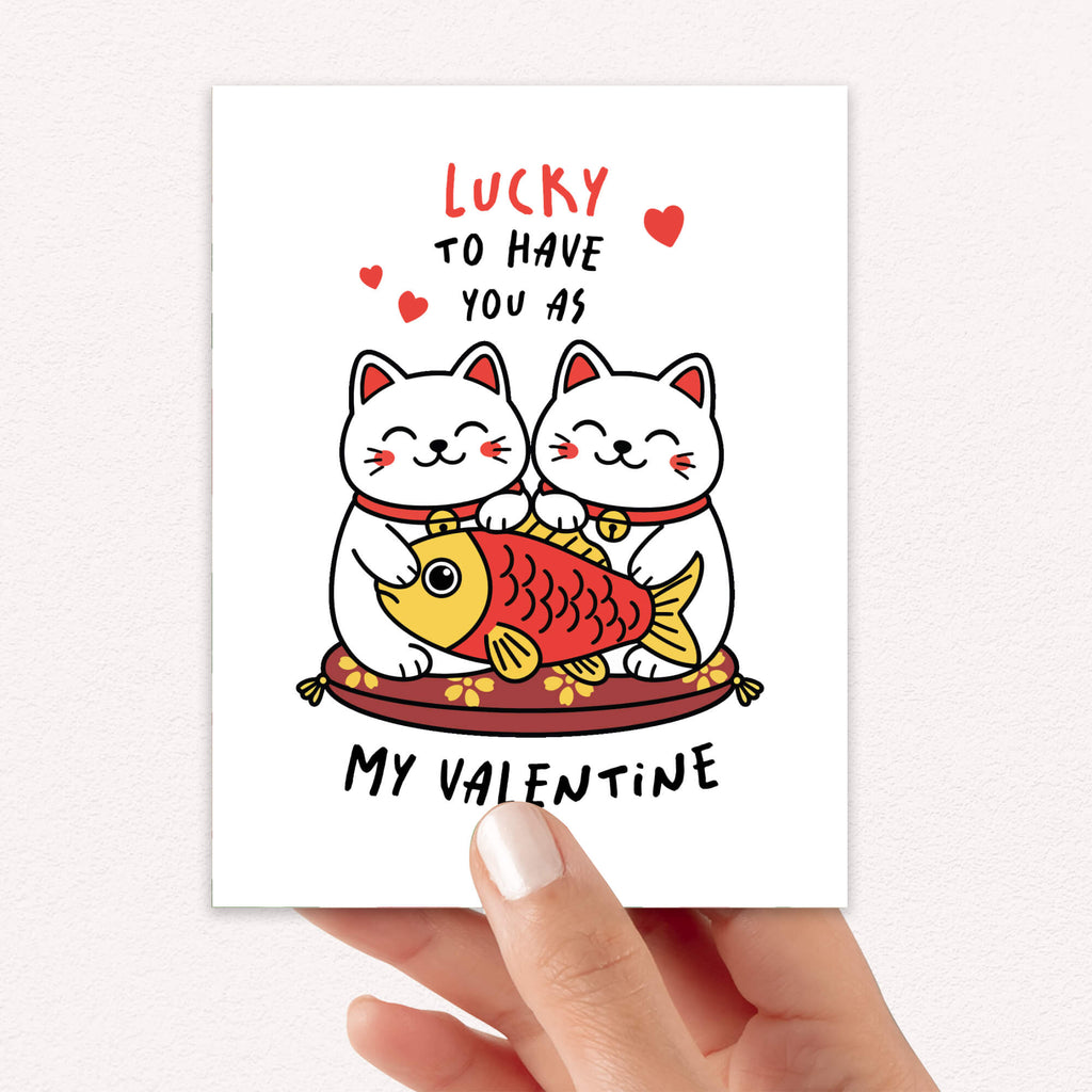 Valentine's Day card with two lucky maneki neko cats and a fish illustration, text 'Lucky to have you as my Valentine'.