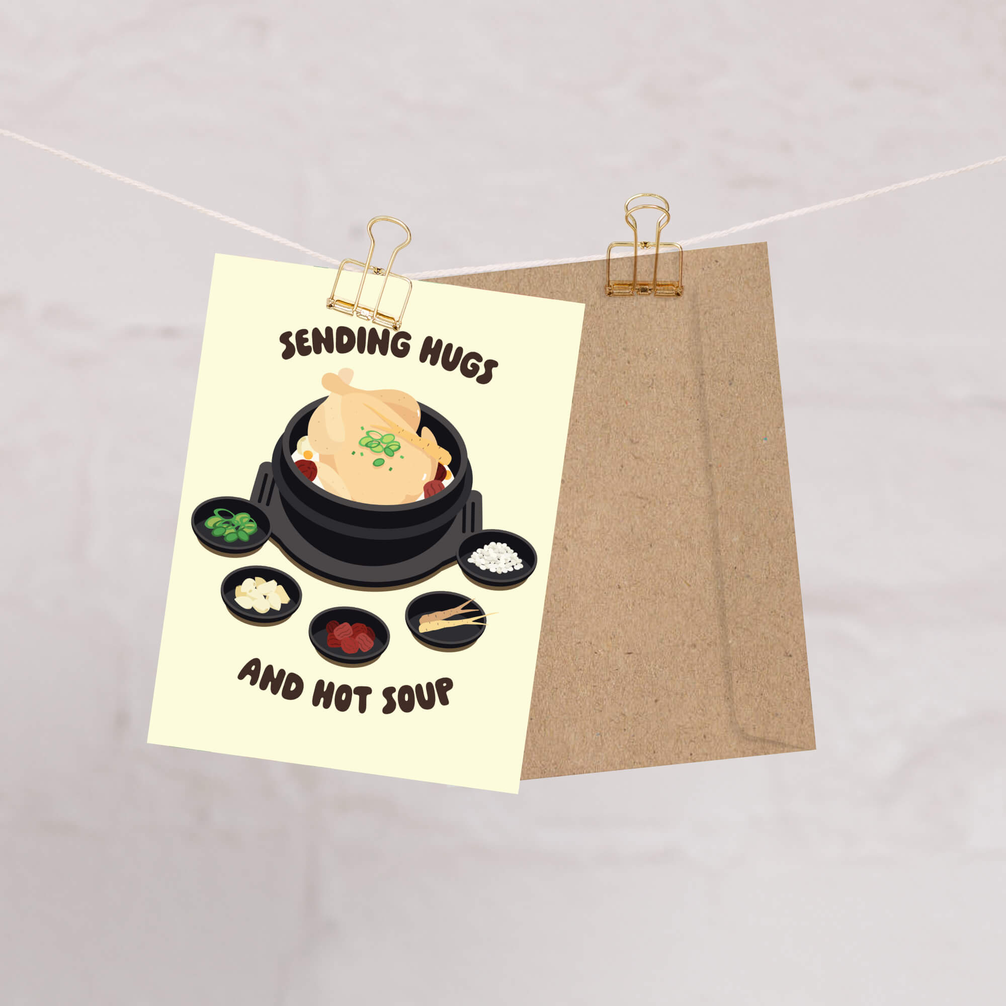 asian Greeting card with a cartoon illustration of a korean chicken soup and text 'Sending Hugs and Hot Soup' on a beige background.
