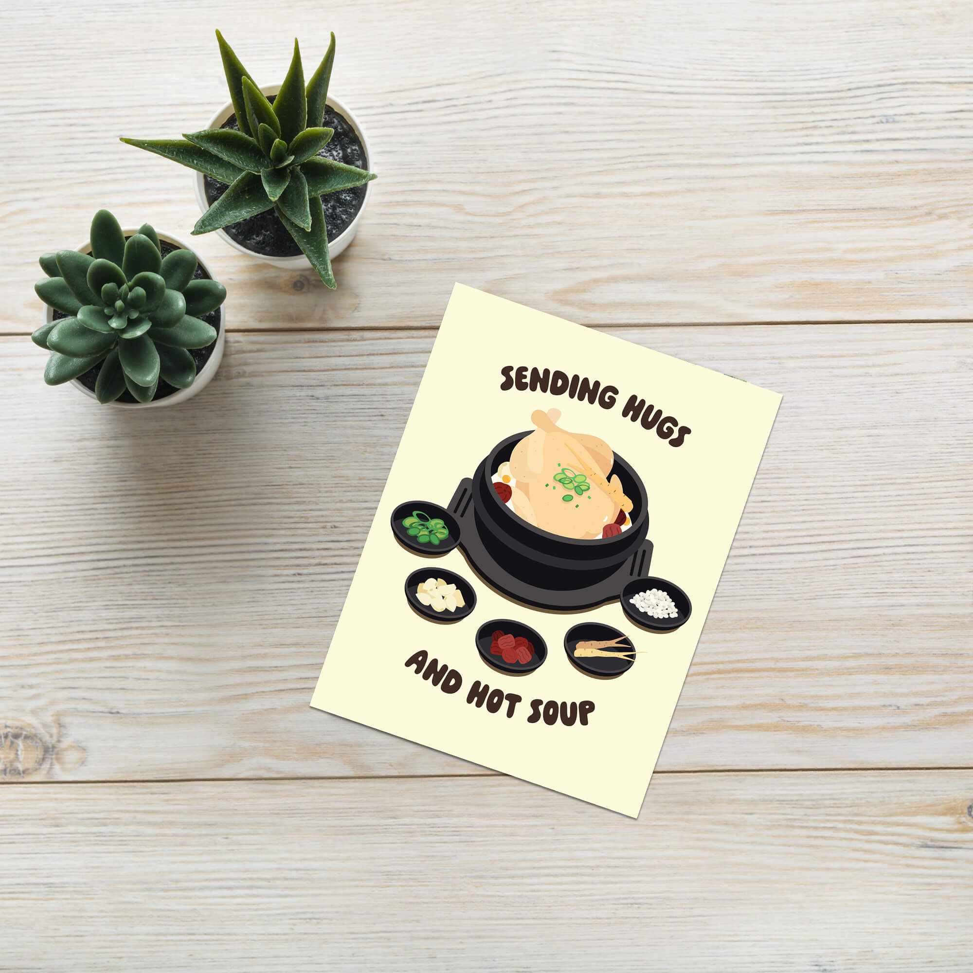 asian Greeting card with a cartoon illustration of a korean chicken soup and text 'Sending Hugs and Hot Soup' on a beige background.