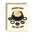 asian Greeting card with a cartoon illustration of a korean chicken soup and text 'Sending Hugs and Hot Soup' on a beige background.