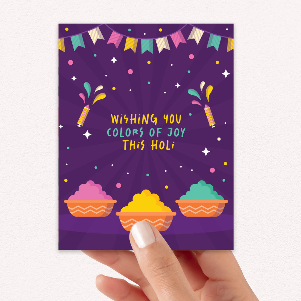 indian Greeting card with colorful design and text 'Wishing you colors of joy this Holi' on a purple background for hindu festival of colors