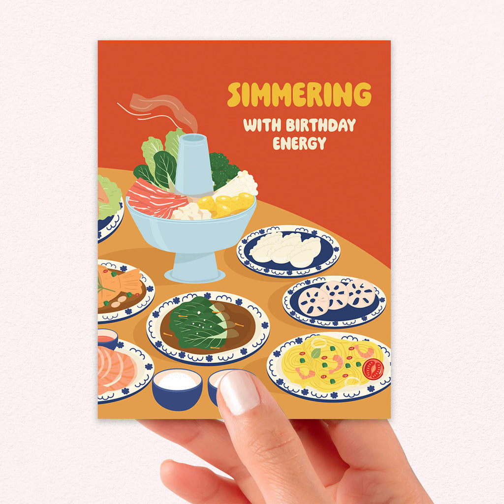 Greeting card with food illustrations and 'Simmering with Birthday Energy' text on an orange background.