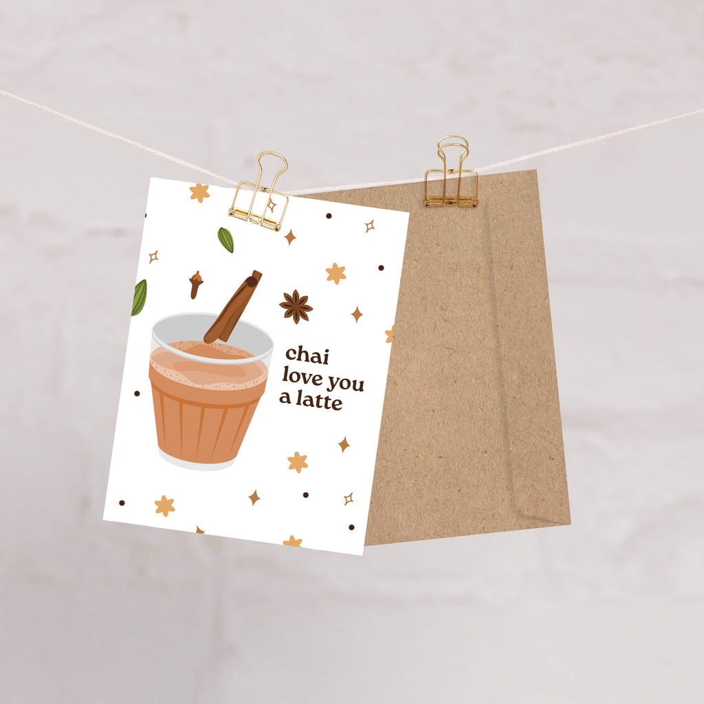 Card with a cup of chai and text 'chai love you a latte' on a white background, attached to a string with a paper clip.