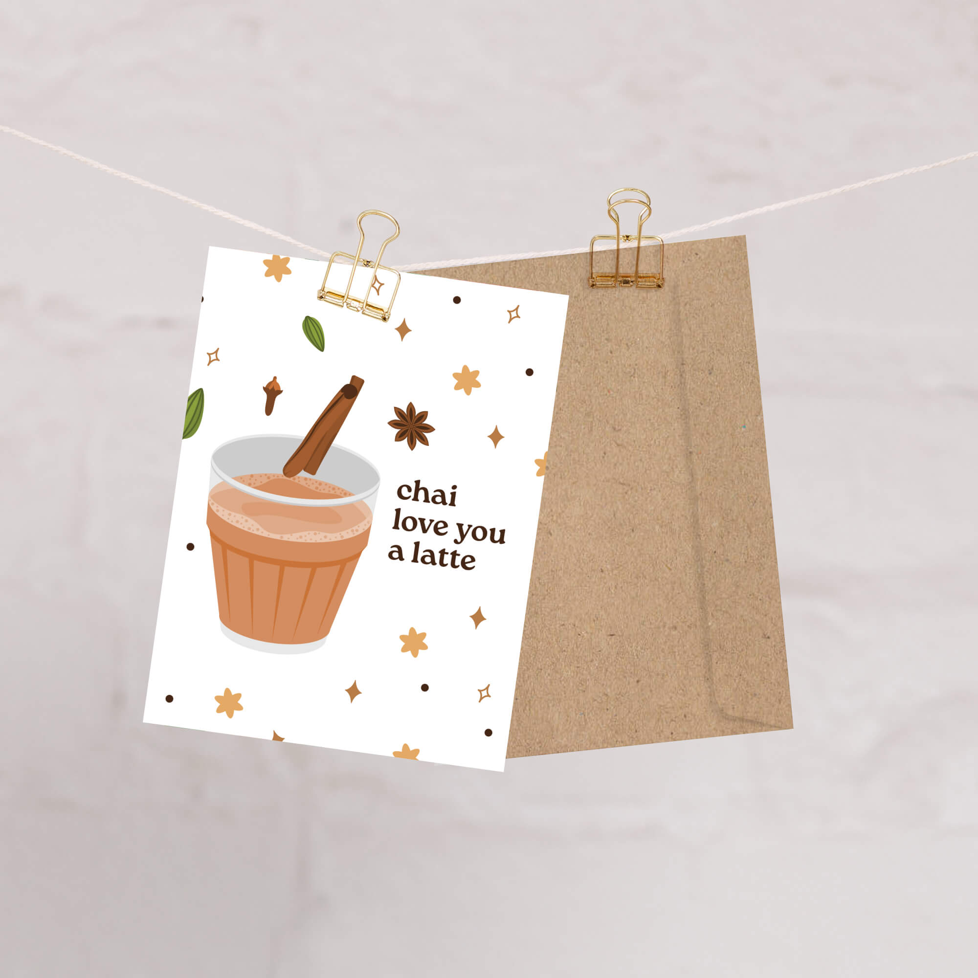 Card with a cup of chai and text 'chai love you a latte' on a white background, attached to a string with a paper clip.
