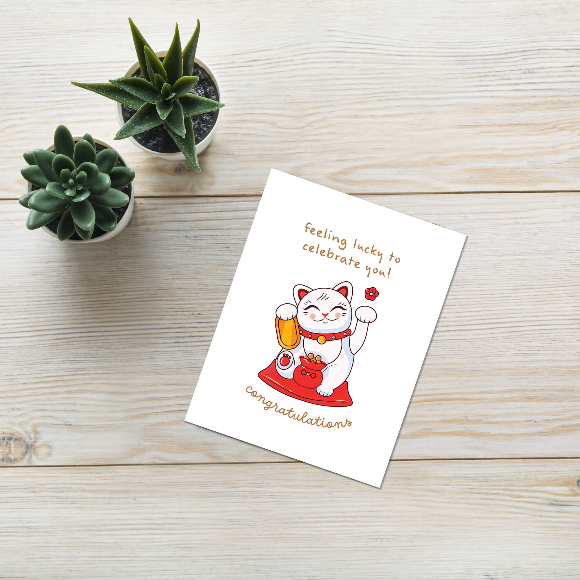 Greeting card with a japanese maneki neko lucky cat illustration and text on a white background that says "feeling lucky to celebrate you. congrats!"