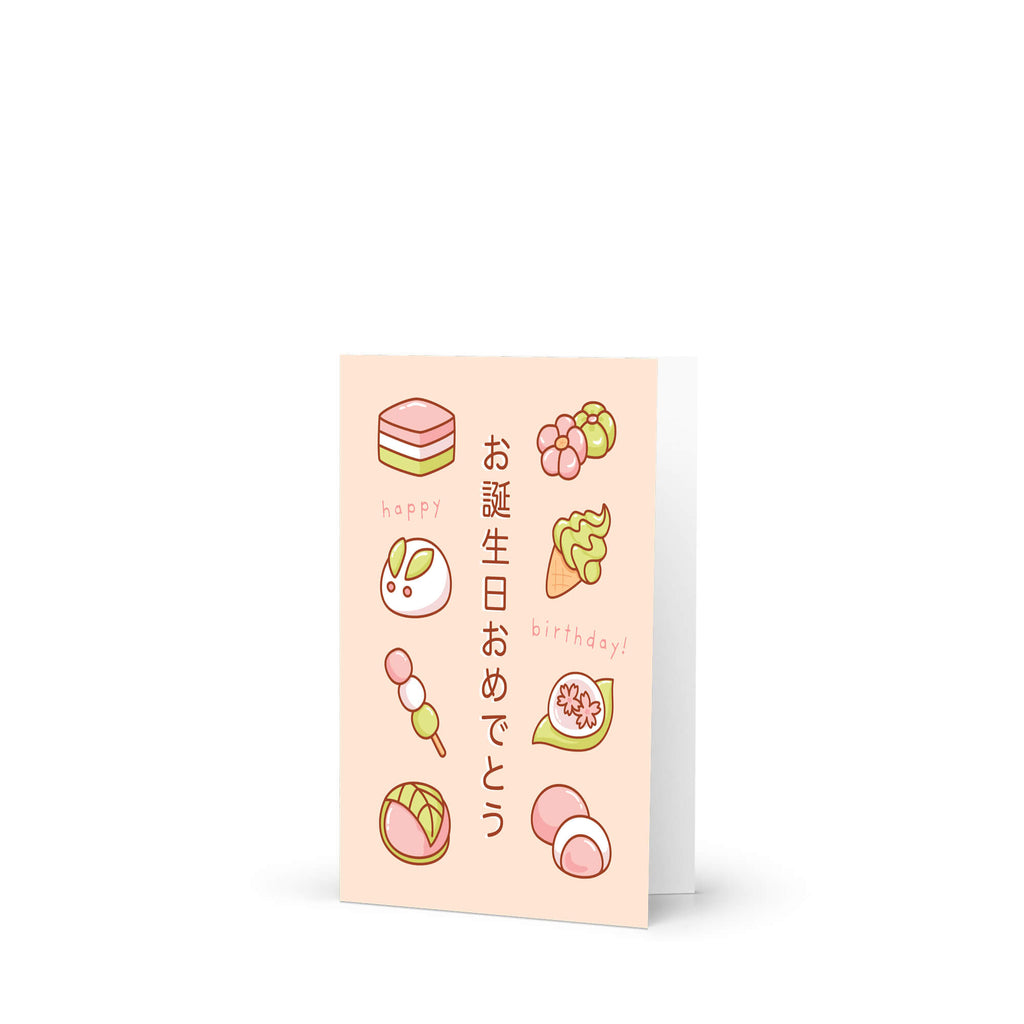 A Japanese birthday greeting card with a pale peach background, featuring cute illustrations of sweets, rice cakes, and Japanese text that says 'Happy Birthday!'.