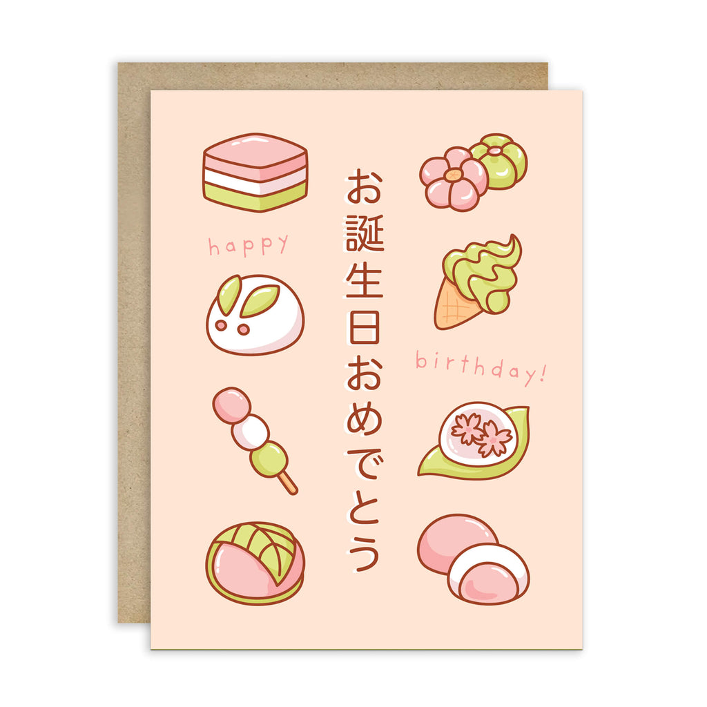 A pink Japanese birthday card with illustrated sweets, flowers, and vertical Japanese text, shown with a kraft envelope behind it on a white background.