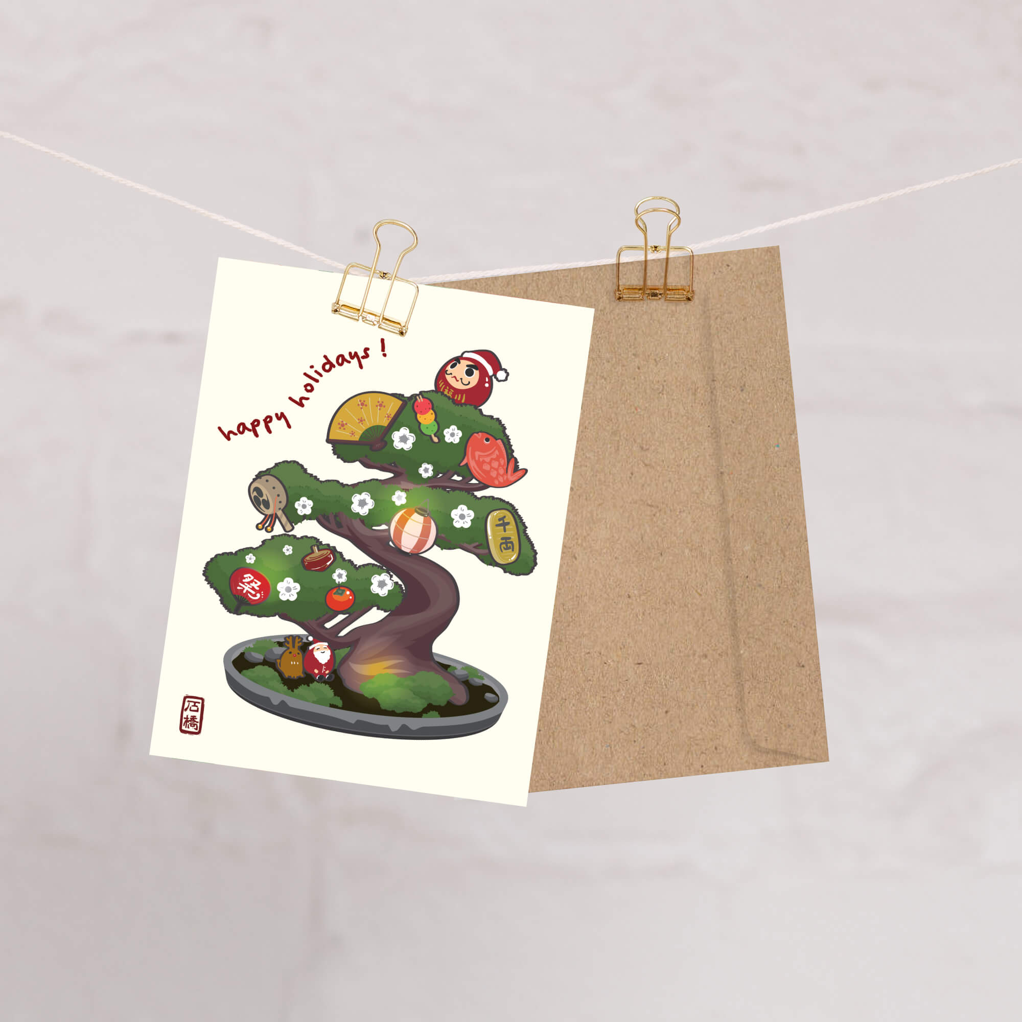 cute japanese christmas card with an Illustration of a bonsai tree decorated with lucky charms, daruma, and red lanterns. Text reads “happy holidays!”