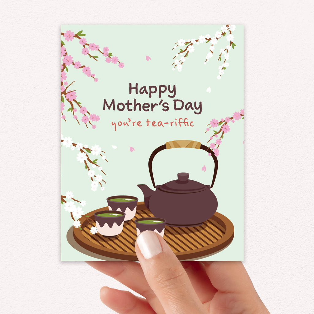 cute Mother's Day card with a brown teapot and cups with green tea and cherry blossom flowers around it with text you're tea-rrific 