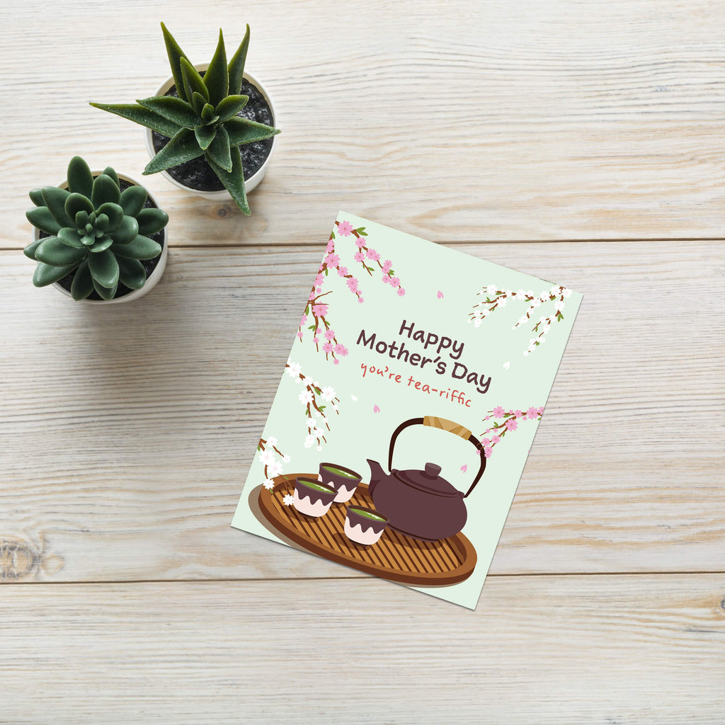 cute Mother's Day card with a brown teapot and cups with green tea and cherry blossom flowers around it with text you're tea-rrific 