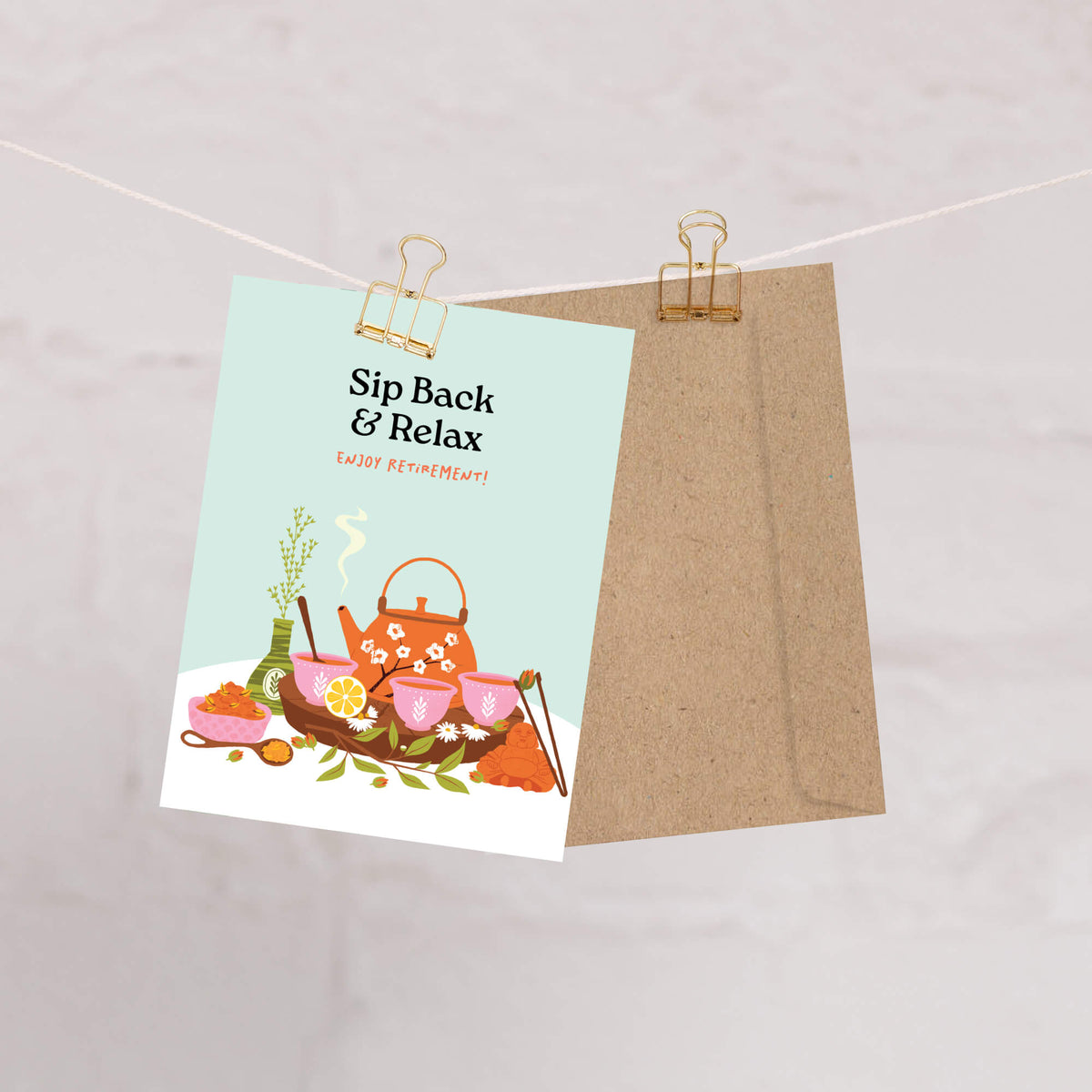 Tea-themed greeting card with teapot illustration and 'Sip Back & Relax' text, attached to a string with a clip.