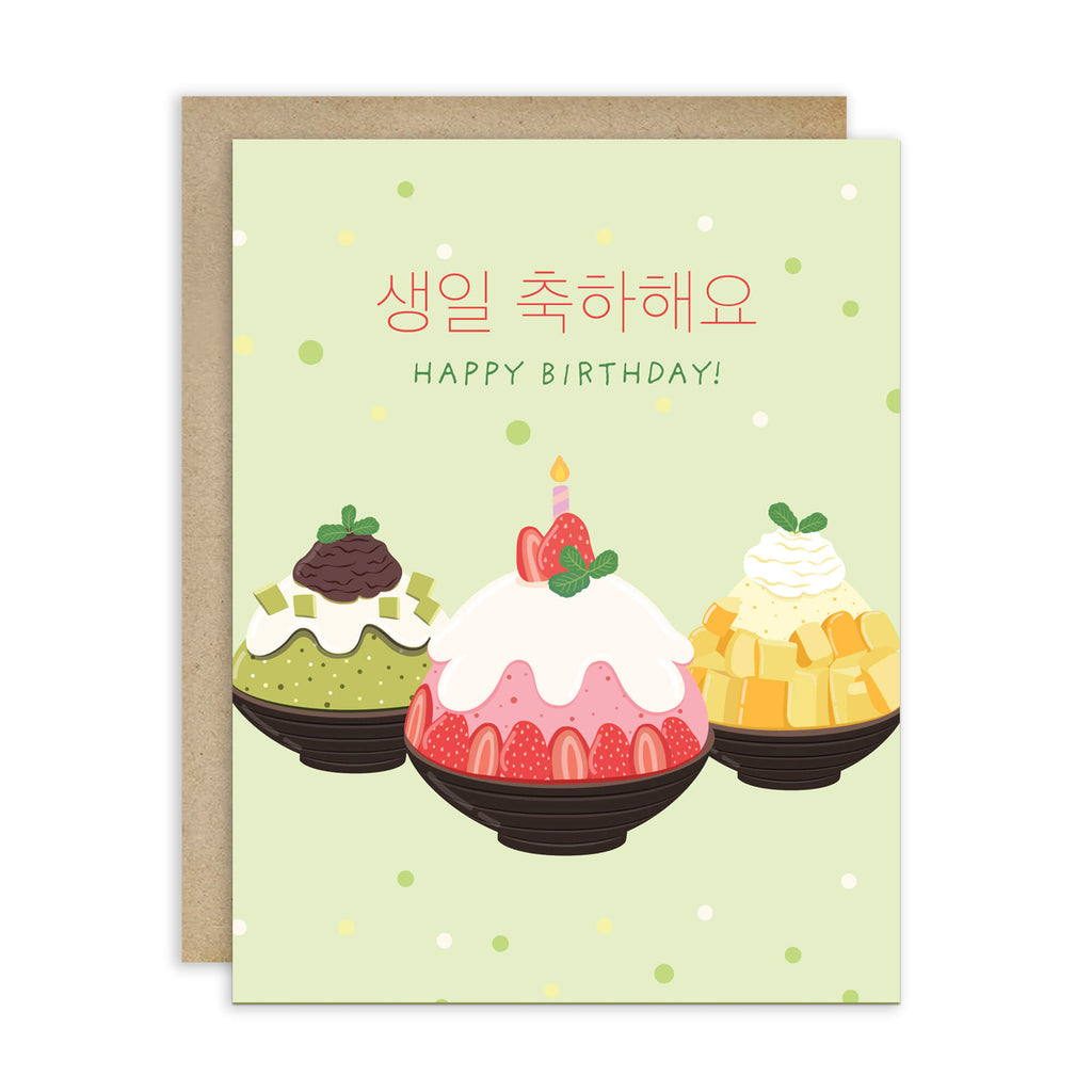 A Korean birthday card with a kraft envelope, featuring three illustrated bingsu shave ice desserts on a pale green background with Korean and English text reading 'HAPPY BIRTHDAY!'.