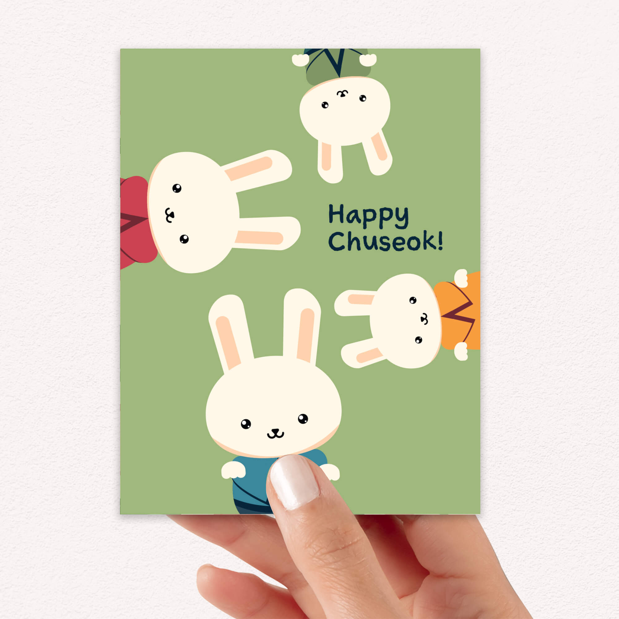 korean harvest thanksgiving greeting Card with cartoon rabbits and 'Happy Chuseok!' text held by a hand on a white background