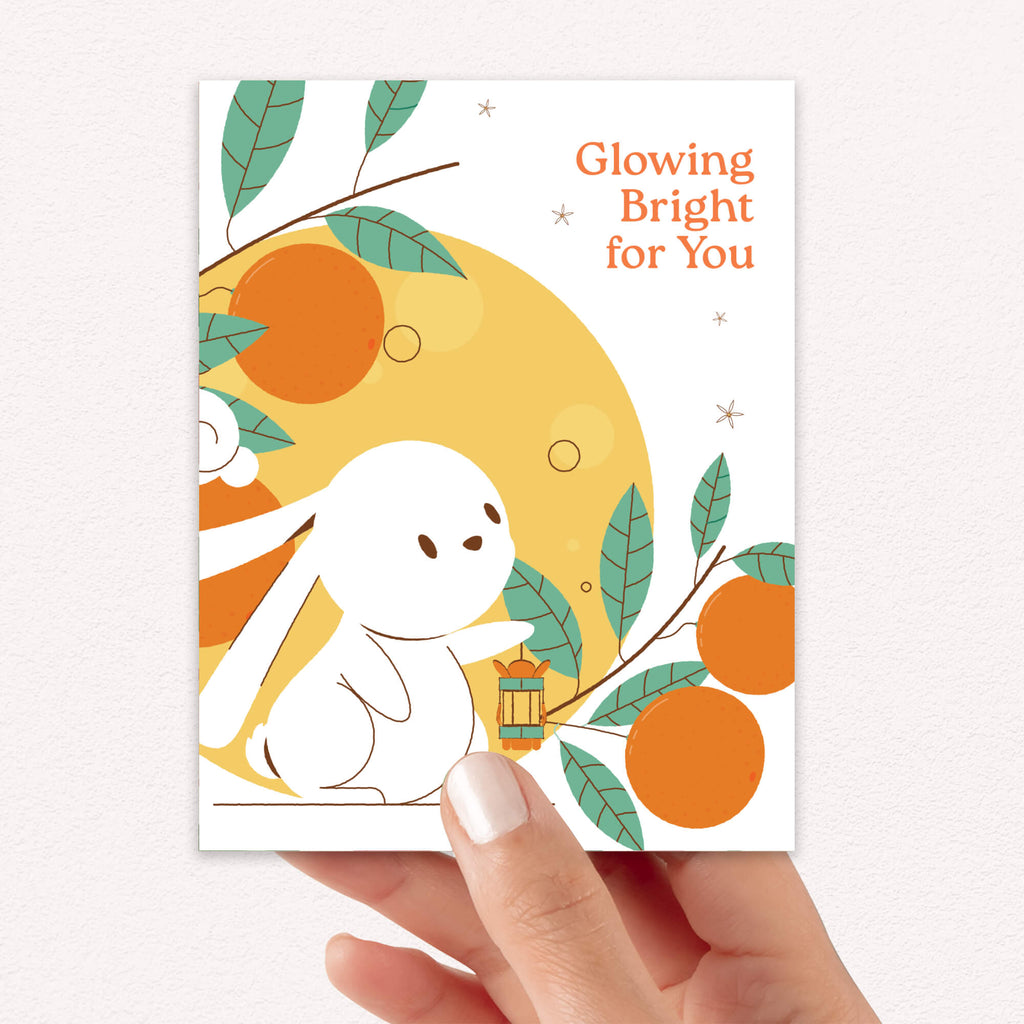 cute asian Greeting card with a white rabbit, orange fruits, and leaves on a white background
