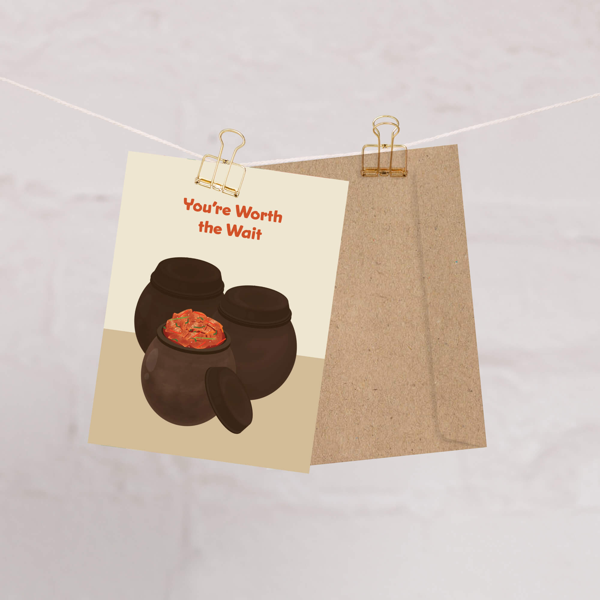 Greeting card with two traditional korean fermenting pots and a kimchi cabbage inside, text 'You're Worth the Wait' on a beige background.