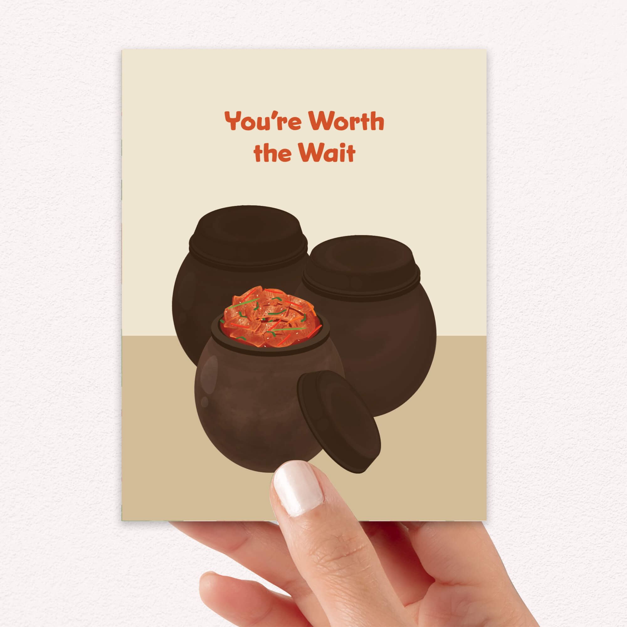Greeting card with two traditional korean fermenting pots and a kimchi cabbage inside, text 'You're Worth the Wait' on a beige background.