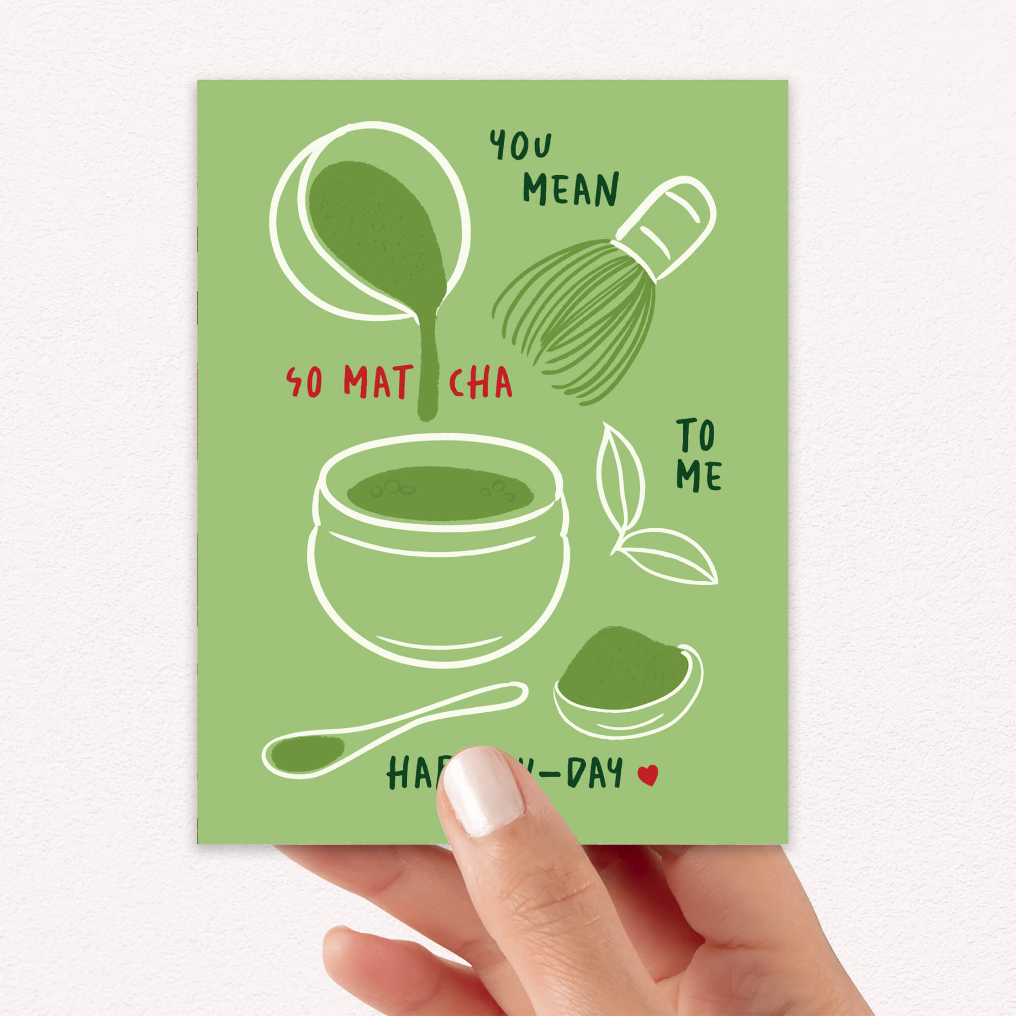 Matcha whisk, bowl, and scoop on green background with “You mean so matcha to me.”