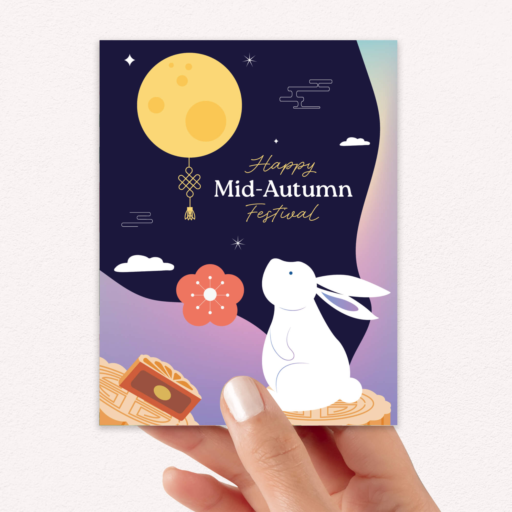 Card with rabbit, moon, and floral design for Mid-Autumn Festival held by a hand.