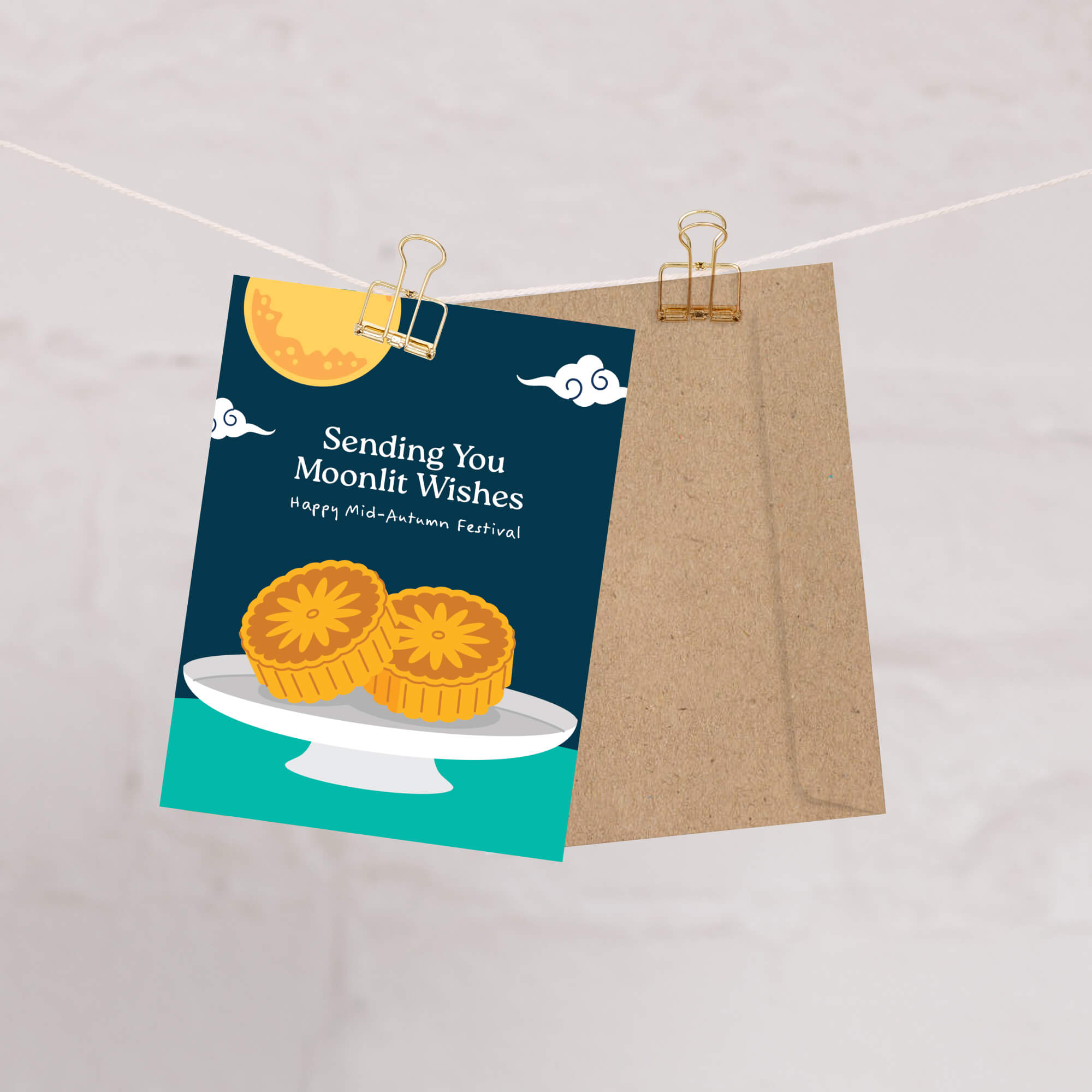 Greeting card with mooncakes and moonlit wishes text, attached to a string with a paper clip.