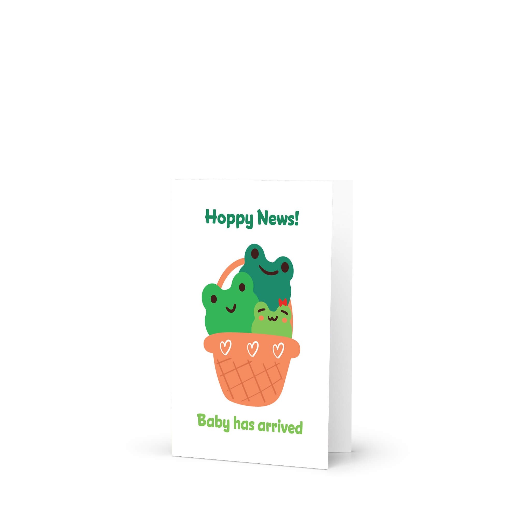 A baby shower card with a cute illustration of three green cartoon frogs in an orange basket, with the text 'Hoppy News!' at the top and 'Baby has arrived' at the bottom, shown on a white background.