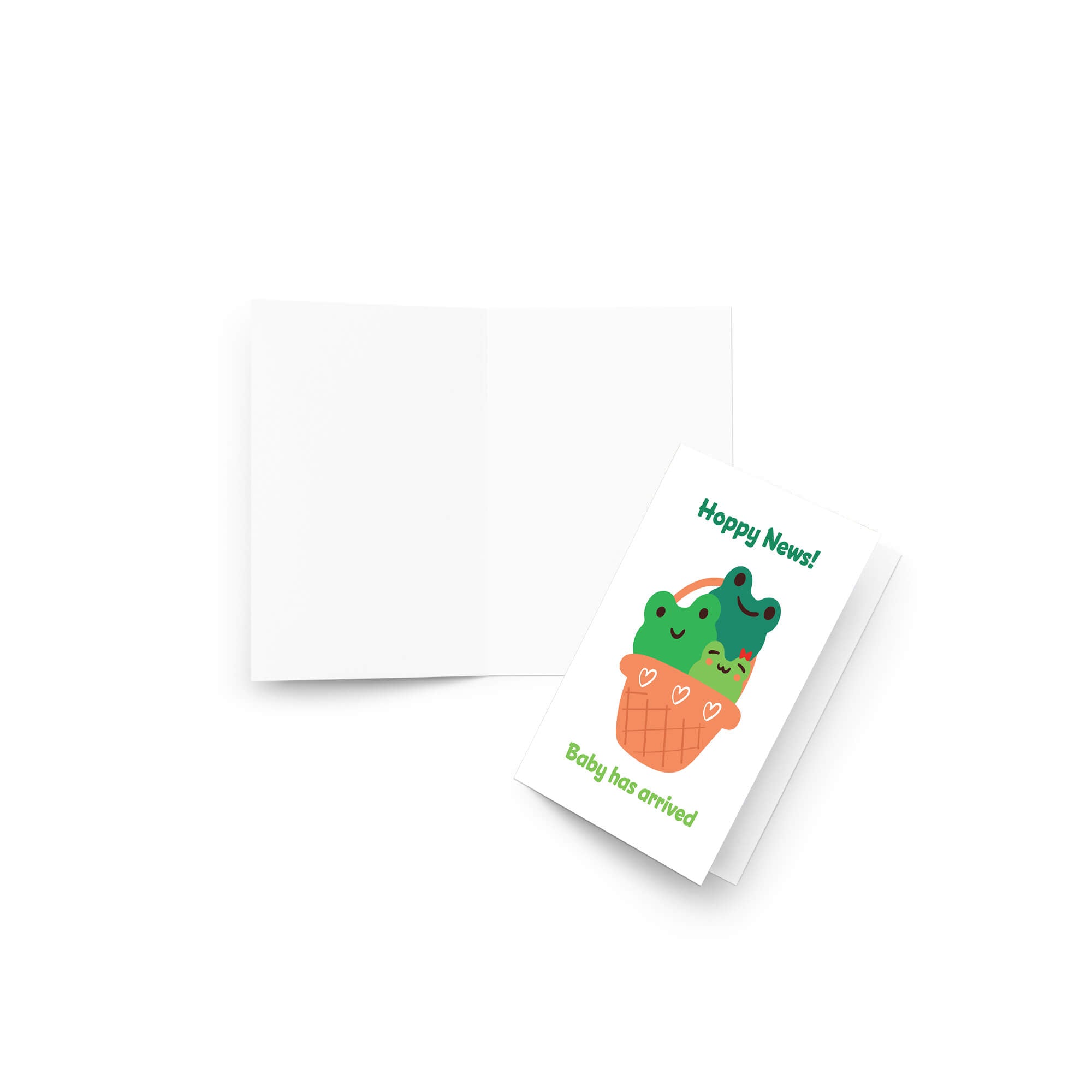 A folded new baby shower card with a cute cartoon illustration of two green frogs in an orange basket, shown next to its matching white envelope on a clean white background.