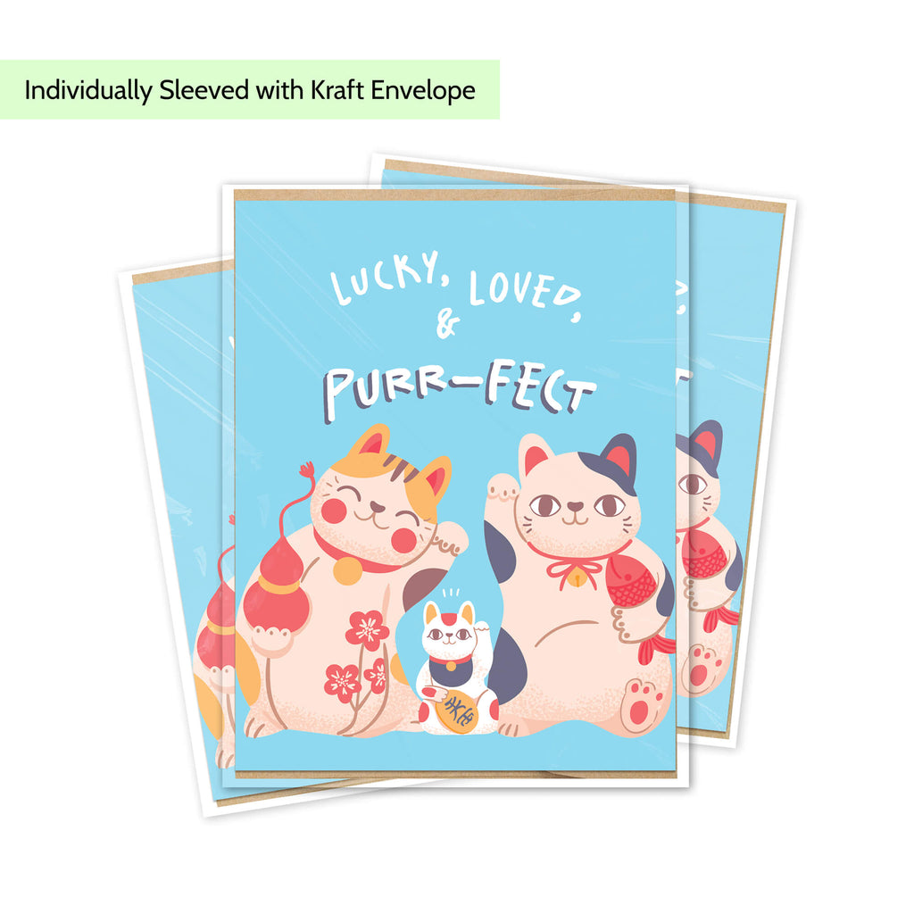 A stack of blue new baby cards featuring cute illustrated maneki-neko cats with red tassels and the text 'LUCKY, LOVED, & PURR-FECT.' A light green banner at the top reads 'Individually Sleeved with Kraft Envelope.