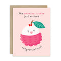 A pink baby shower card with a cute cartoon lychee illustration and the text 'the sweetest lychee just arrived' and 'congratulations!', shown with a brown kraft envelope behind it on a white background.