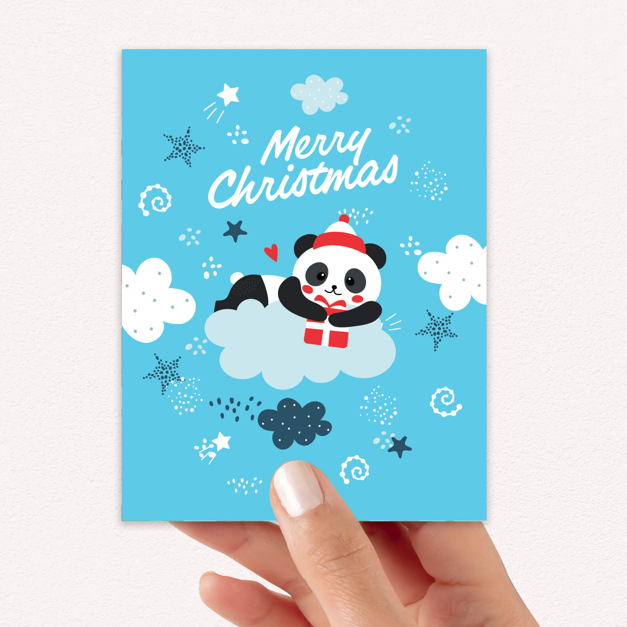 cute christmas card with A panda wearing a Santa hat floats on a cloud holding a red gift box. Surrounded by stars and snowflakes. Text reads “Merry Christmas.”
