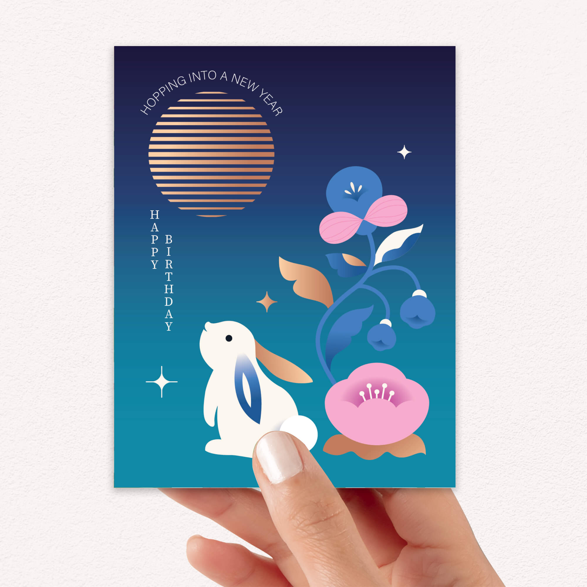 birthday Greeting card with a rabbit and floral design, held by a hand.