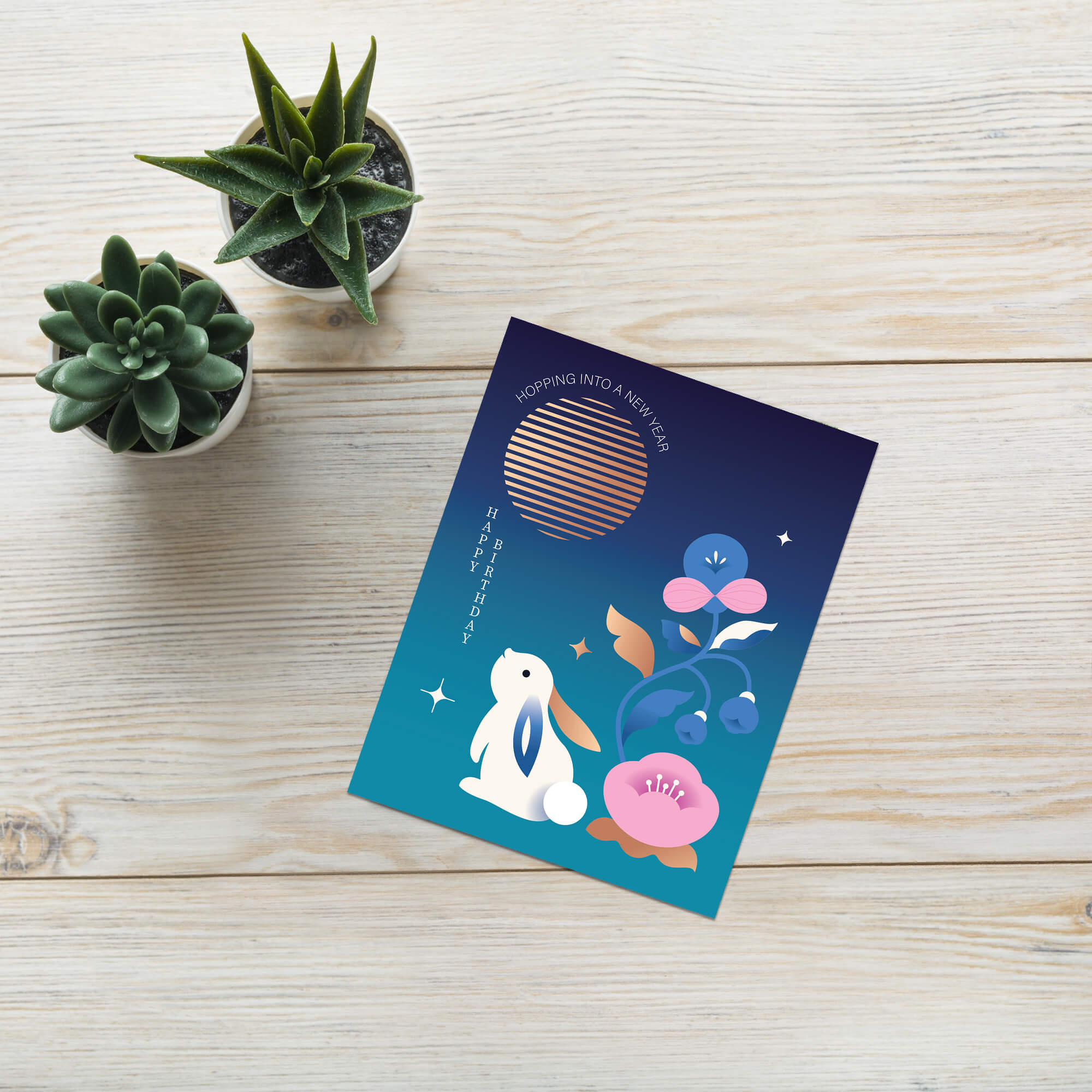 birthday Greeting card with rabbit and floral design on a wooden surface with succulents.