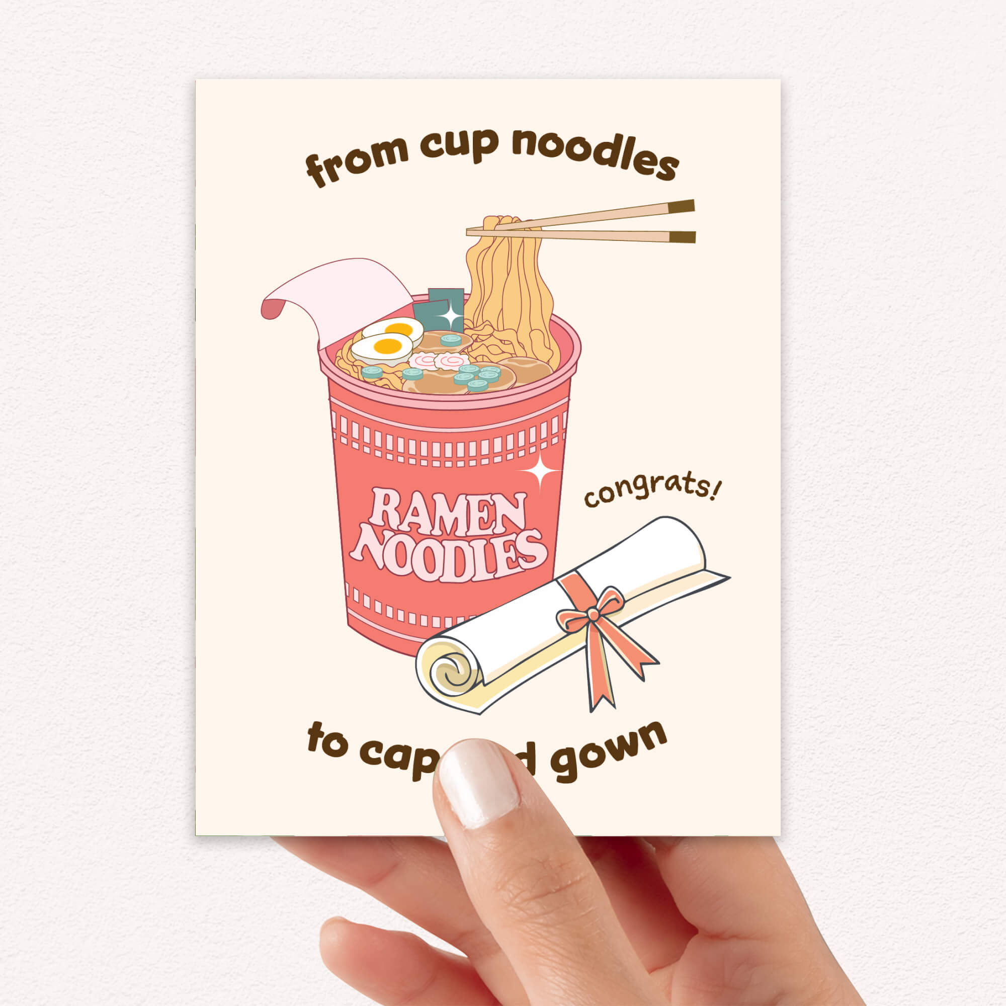 care graduation card with a cup of ramen noodles and text 'From cup noodles to cap and gown' on a beige background.