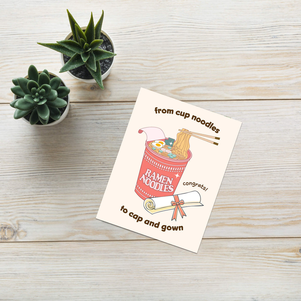 care graduation card with a cup of ramen noodles and text 'From cup noodles to cap and gown' on a beige background.