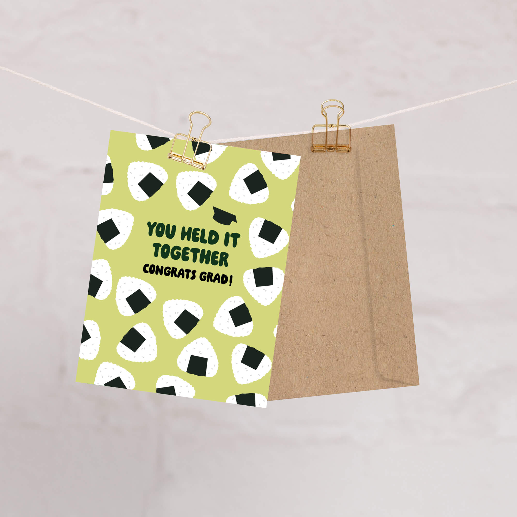 Graduation card with japanese onigiri rice ball pattern and text 'You held it together. Congrats grad!' on a white background.