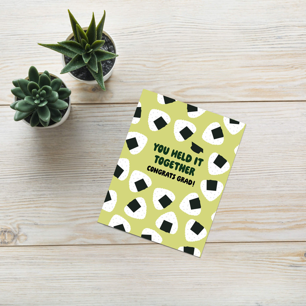 Graduation card with japanese onigiri rice ball pattern and text 'You held it together. Congrats grad!' on a white background.