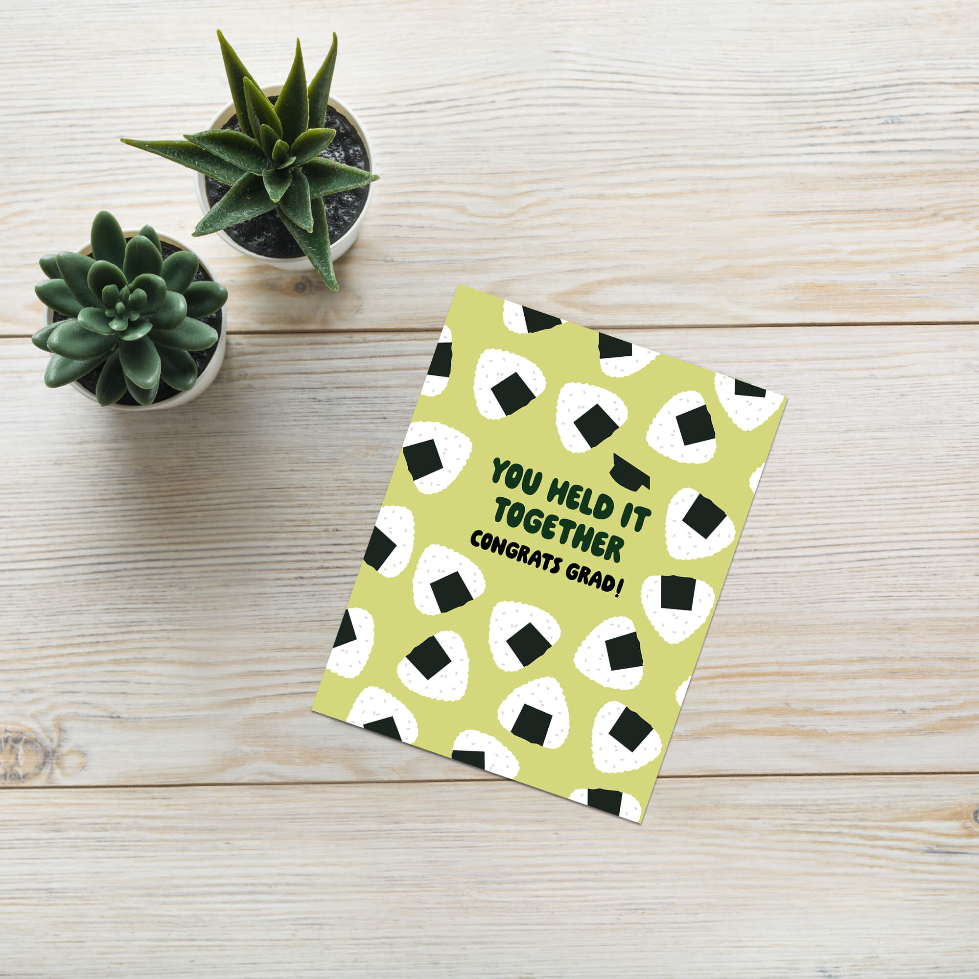 Graduation card with japanese onigiri rice ball pattern and text 'You held it together. Congrats grad!' on a white background.