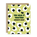 Graduation card with japanese onigiri rice ball pattern and text 'You held it together. Congrats grad!' on a white background.