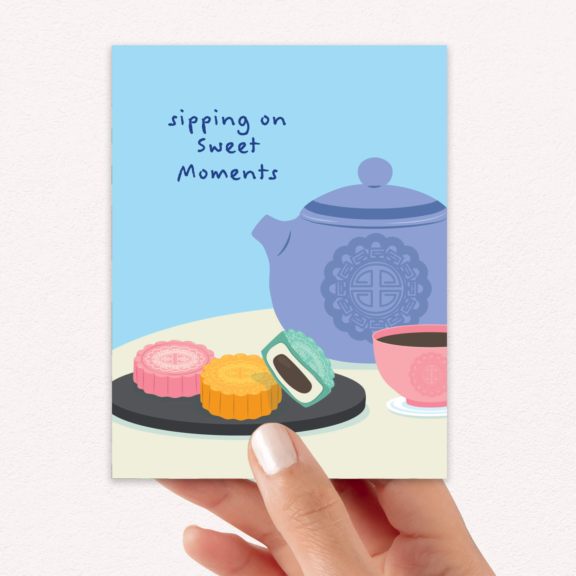 asian greeting Card with a blue teapot, pink teacup, and cookies on a white background with 'sipping on sweet moments' text.