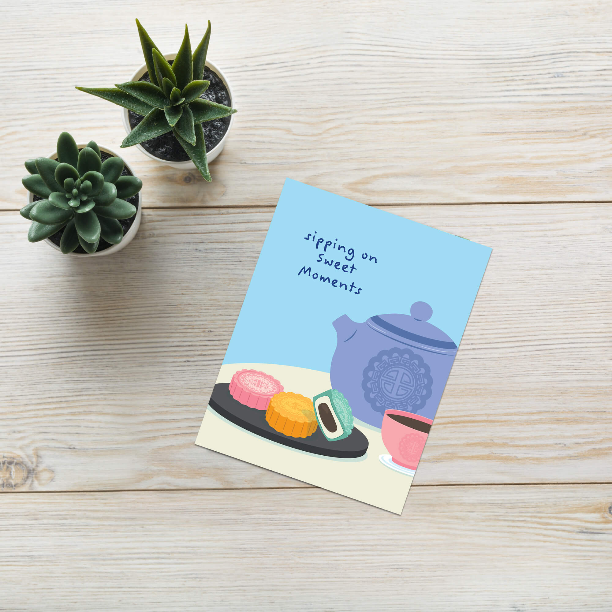 asian greeting Card with a blue teapot, pink teacup, and cookies on a white background with 'sipping on sweet moments' text.
